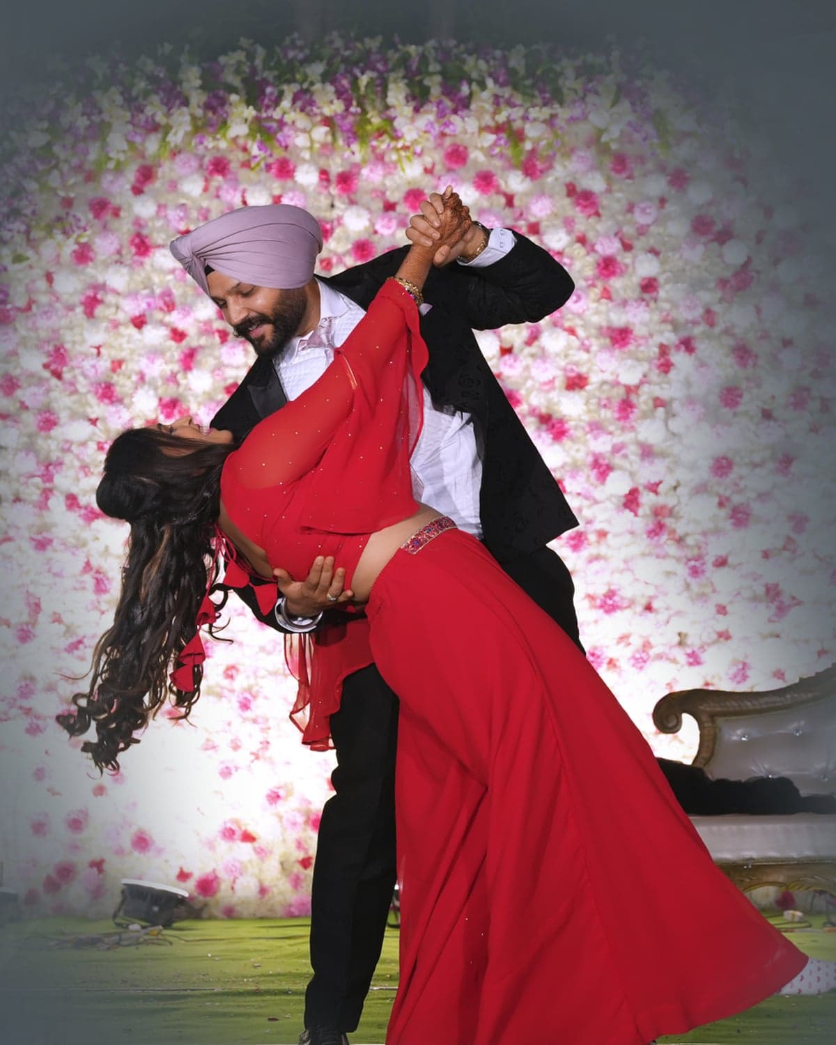 Sirish and Tejaswini sharing a dance dip in front of a flower wall