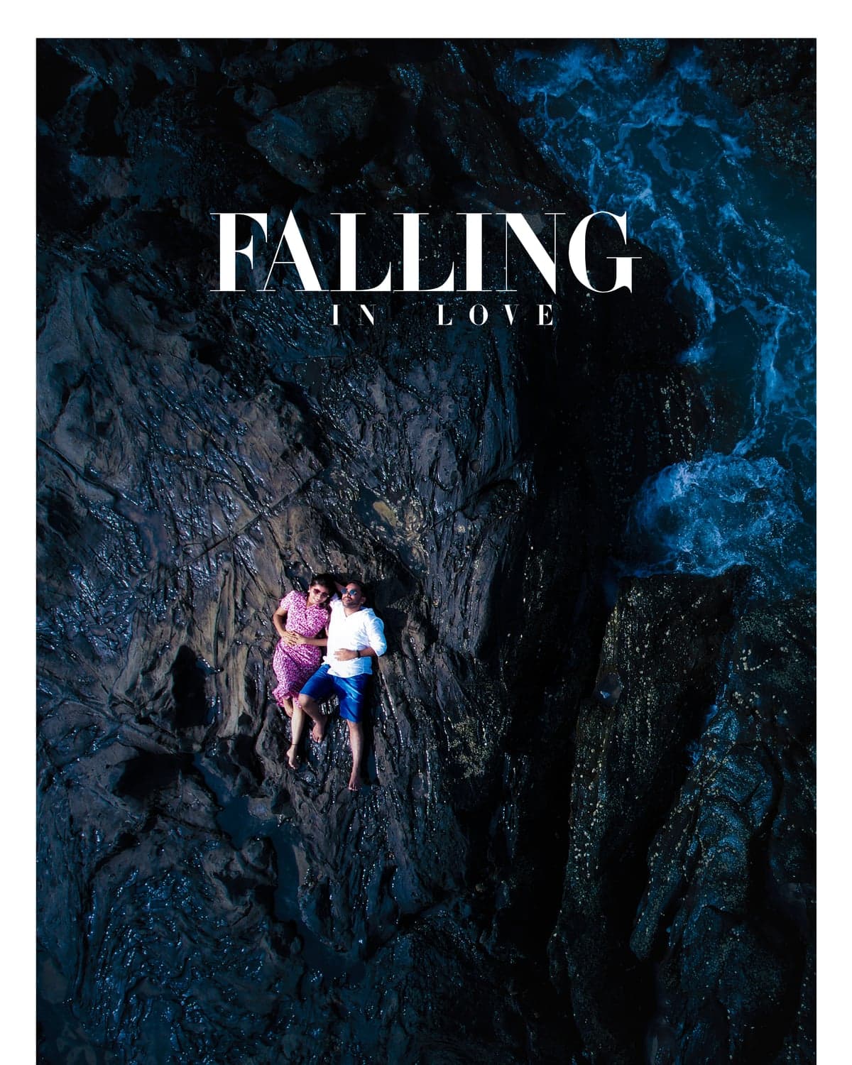 Aerial shot of the couple lying together on ocean rocks, styled as a "Falling in Love" poster