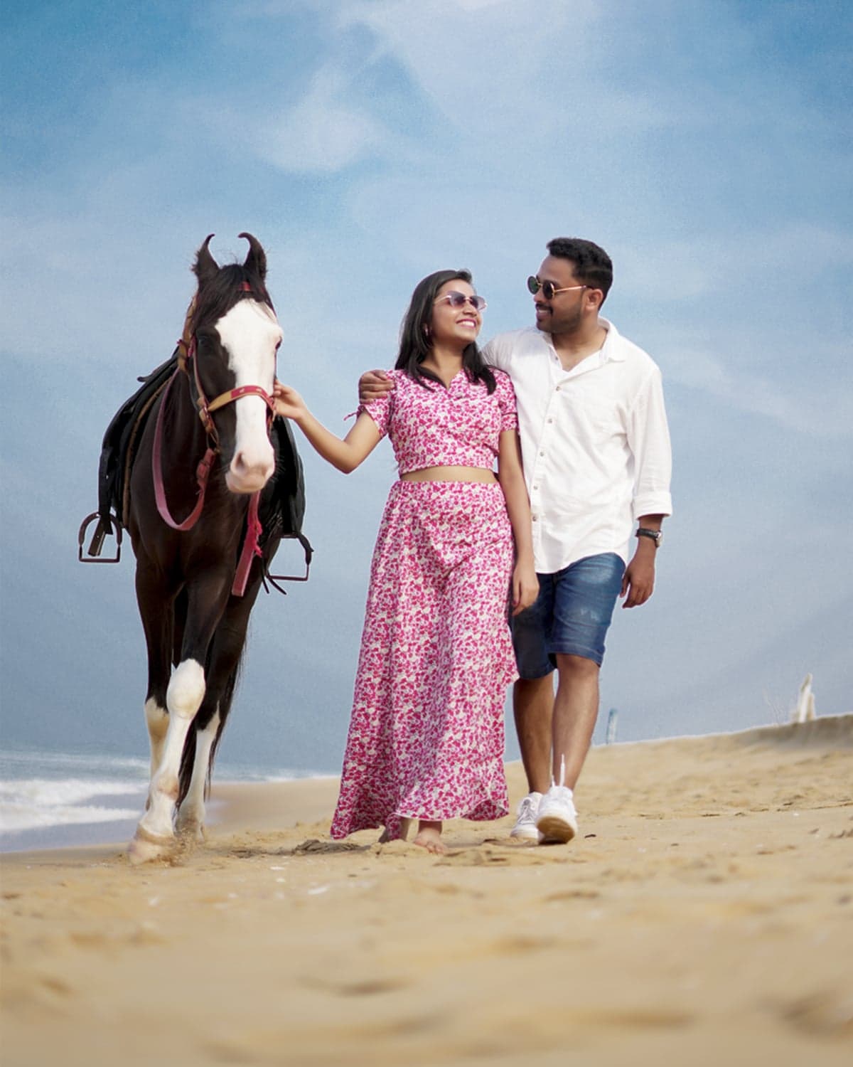 Beach photo of the couple walking with a horse along the shore